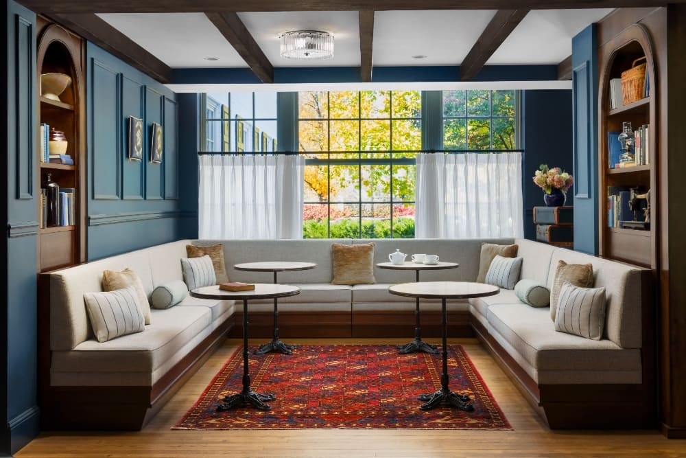 Bright window seating area with cozy sectional couches and decorative pillows at the Nittany Lion Inn.
